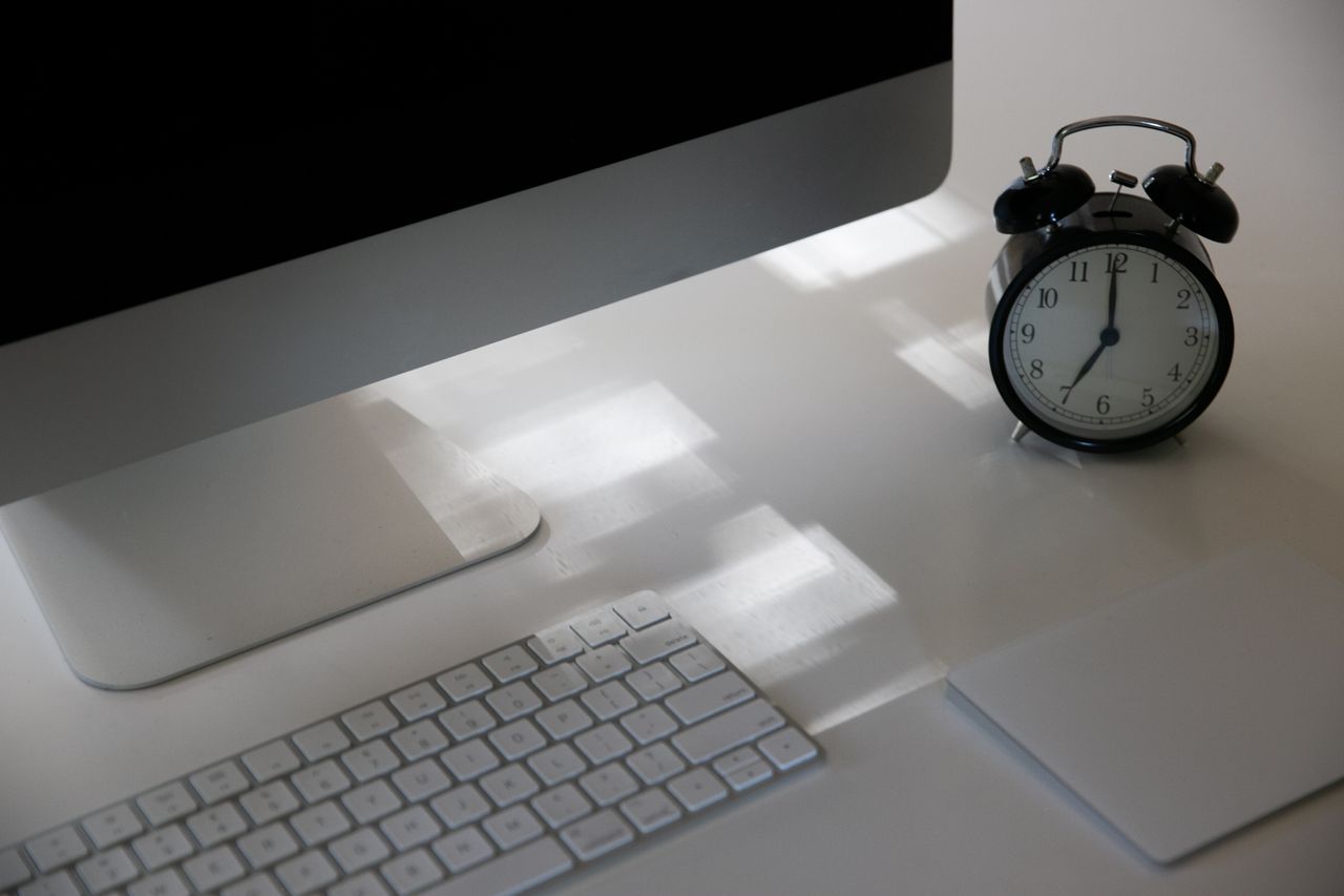 Elevate productivity with a sleek workspace featuring a computer, keyboard, and analogue clock.